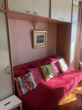 A room featuring a red sofa bed and built-in wardrobes. - image 3