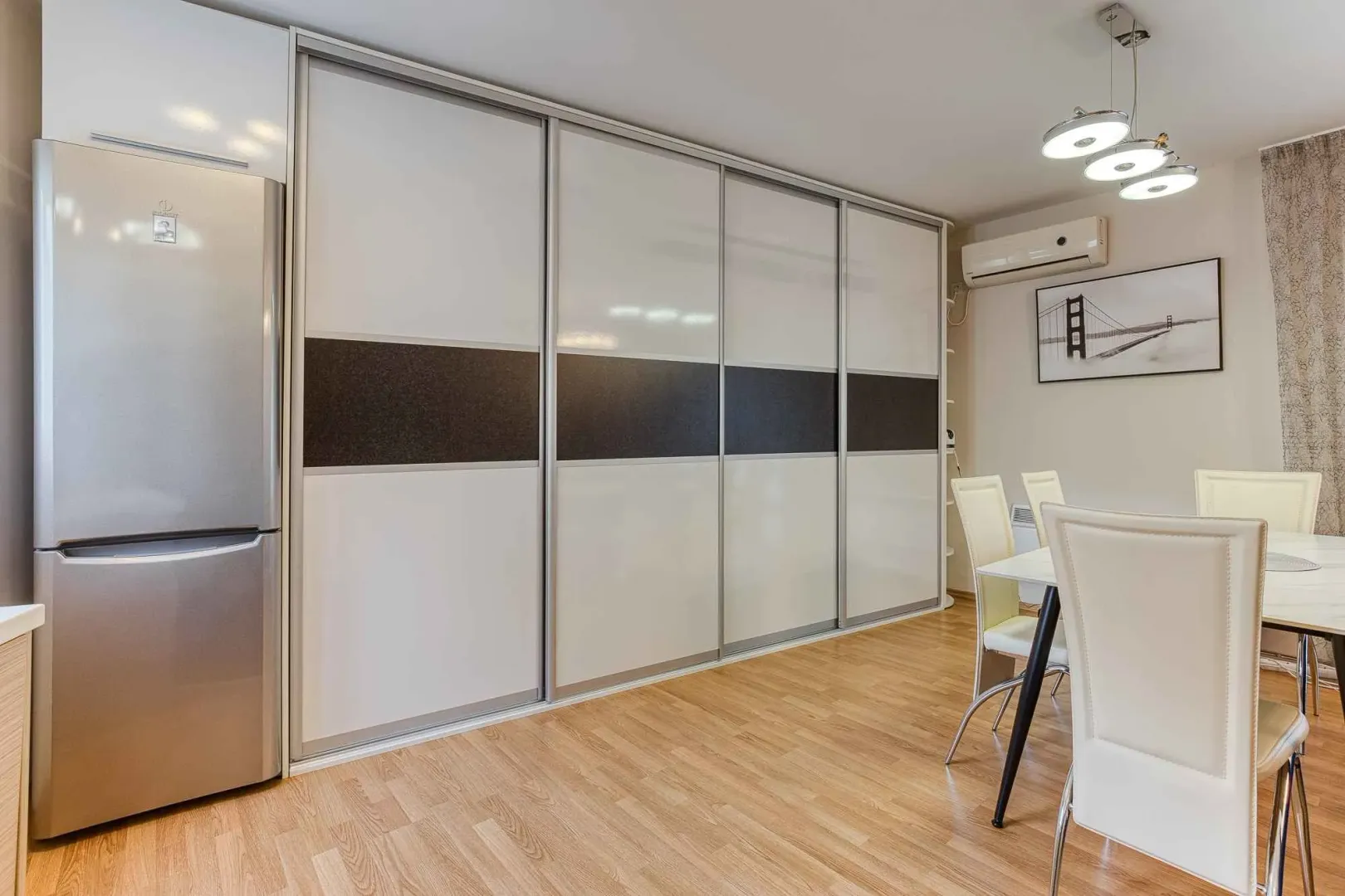 Living room with a large built-in wardrobe, refrigerator, and dining table.