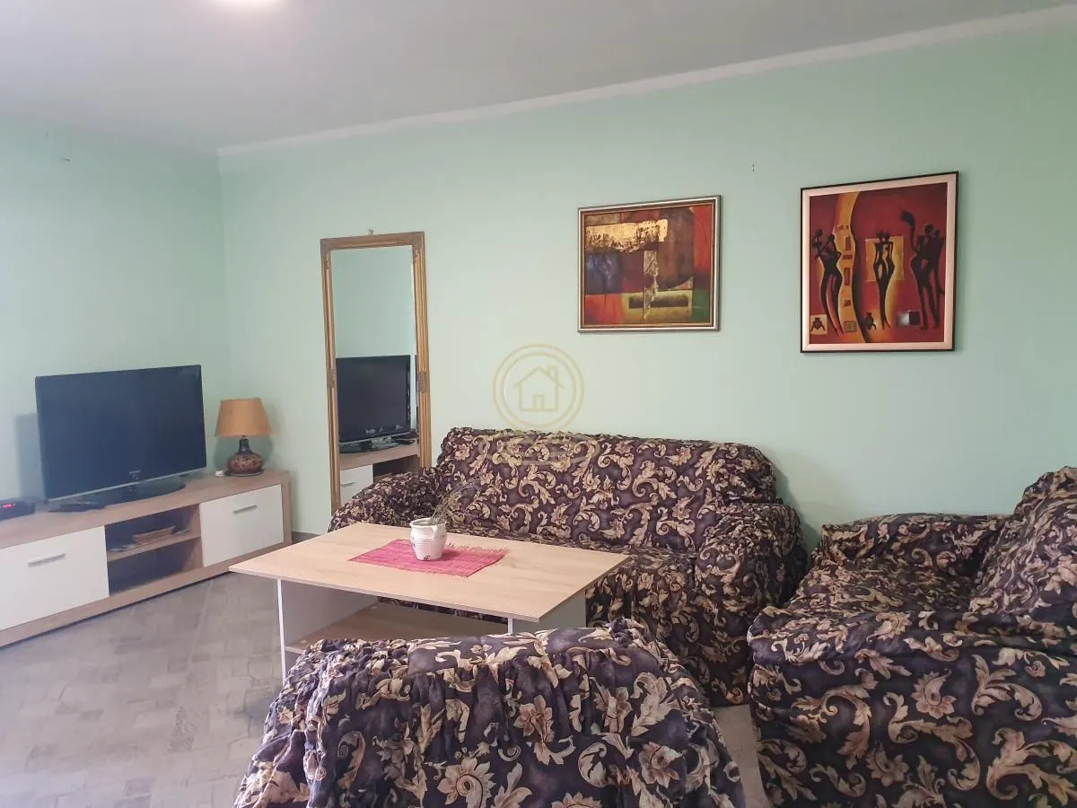 Dnevna soba sa garniturom, stočićem i televizorom.
