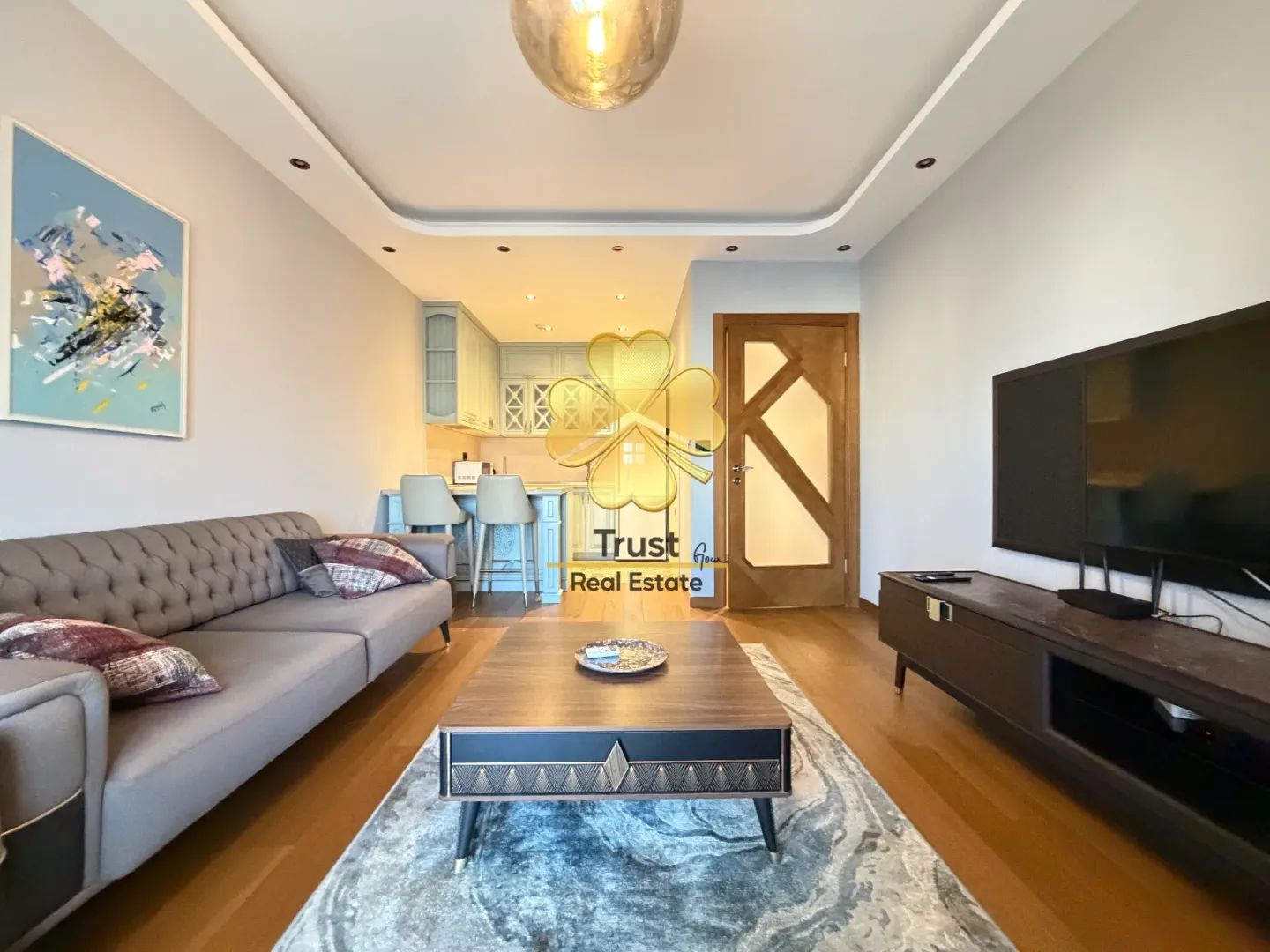 Modern living room with a sofa, coffee table, and a view of the kitchen.