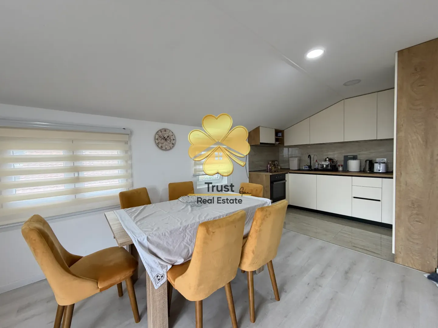 Dining area with a table and yellow chairs and a kitchen in the background.