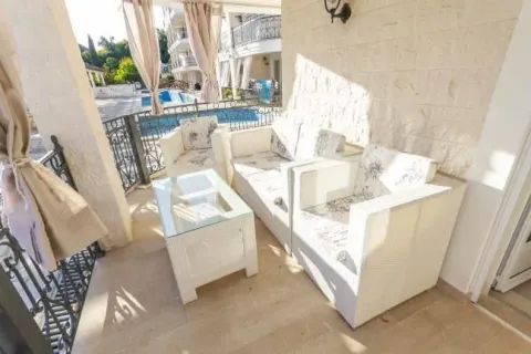 Covered terrace with seating furniture and a pool view. - image 7