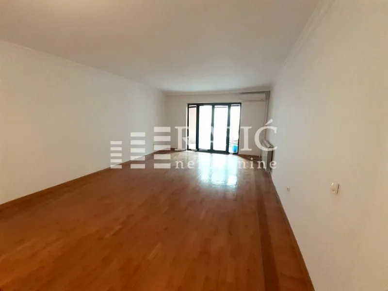 Empty spacious room with parquet flooring and terrace access.