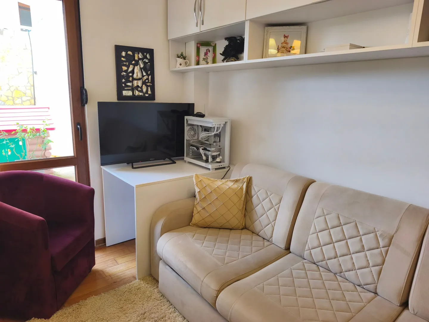 Dnevna soba sa bež garniturom, foteljom, radnim stolom i televizorom.