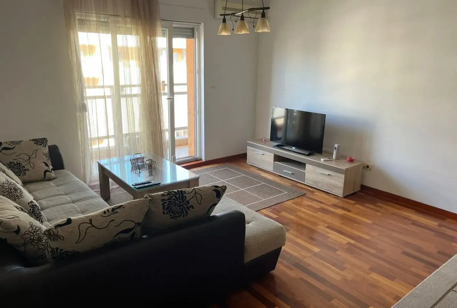 Living room with a sofa, television, and balcony access.