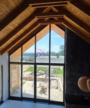 Dnevni boravak sa visokim plafonom, drvenim gredama i velikim staklenim zidom. - image 7