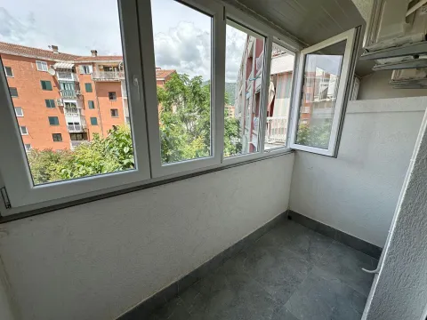 Zastakljeni balkon sa pogledom na okolne zgrade i zelenilo. - image 17