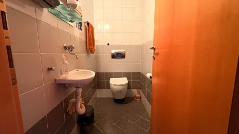Smaller tiled bathroom with a sink and a toilet. - image 10