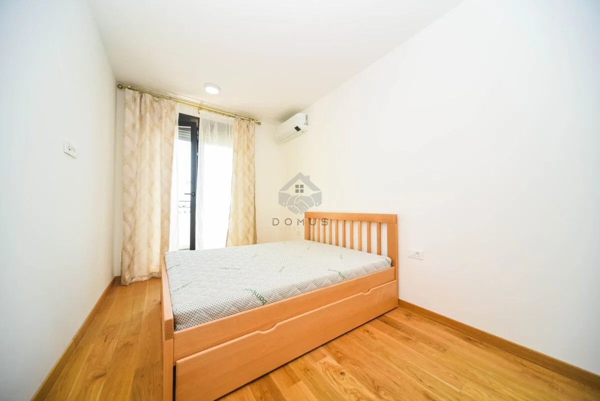 Bedroom with a wooden bed, parquet flooring, and balcony doors.