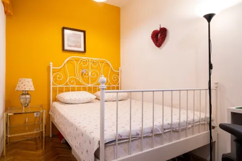 Furnished bedroom with a white metal bed and a yellow accent wall. - image 18