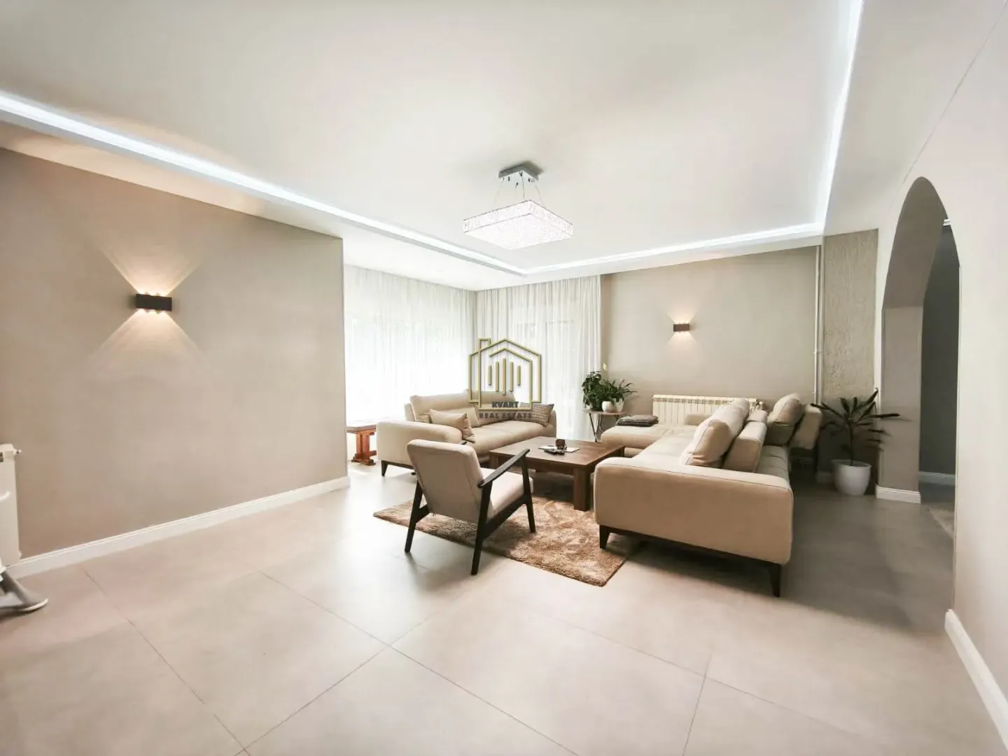Spacious living room with a sofa set, coffee table, and modern lighting.