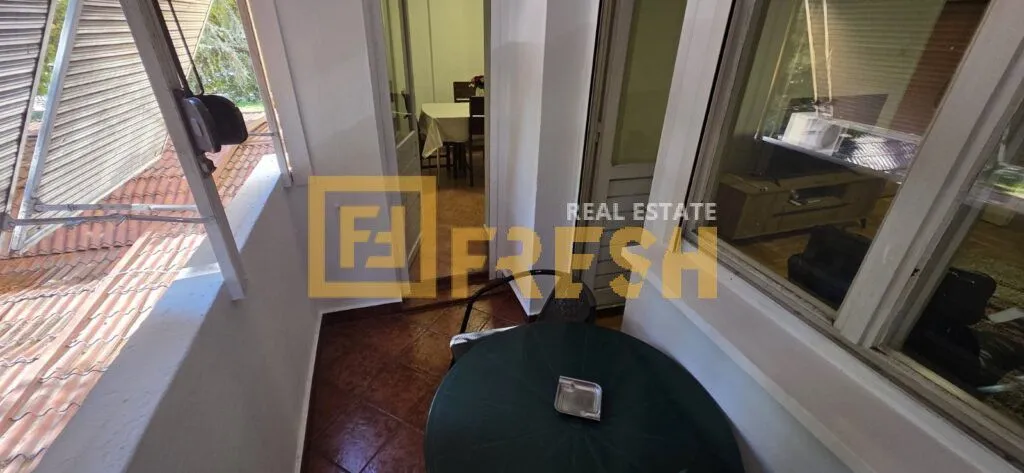 Natkriveni balkon sa garniturom za sjedenje i pogledom na krovove.