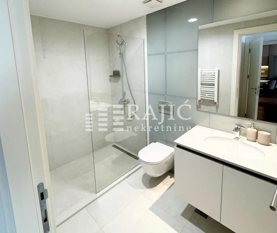 Modern bathroom with a walk-in shower and a white vanity unit.