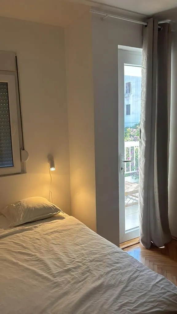 Manja spavaća soba sa krevetom i izlazom na terasu.