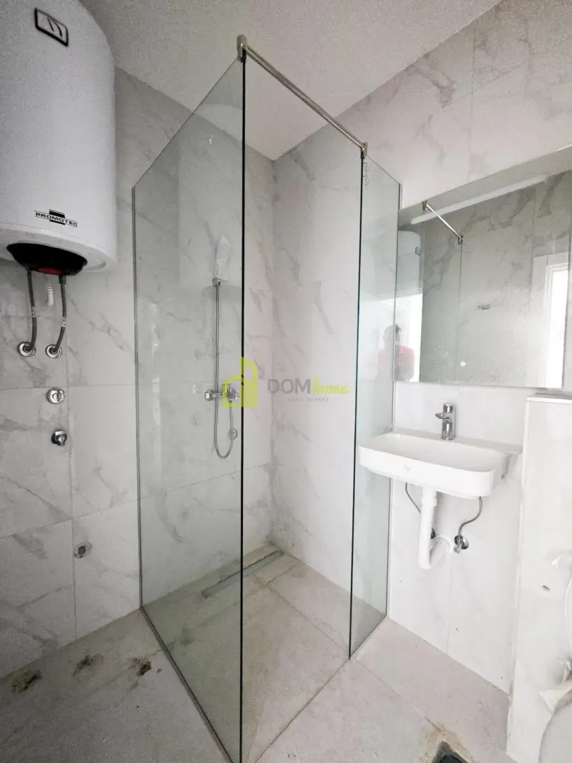 Bathroom with a shower cabin, washbasin, and water heater.