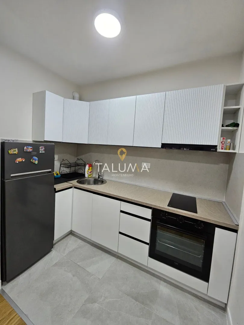 Small kitchen with white cabinets, refrigerator, and built-in oven.