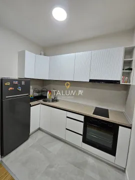 Small kitchen with white cabinets, refrigerator, and built-in oven. - image 3