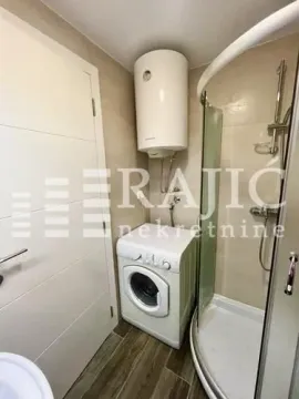 Smaller bathroom with a shower cabin, water heater, and washing machine. - image 11