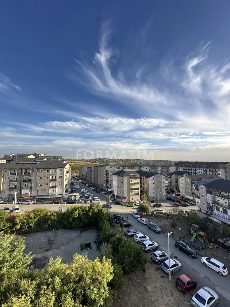 Pogled sa prozora na okolne stambene zgrade i parking.