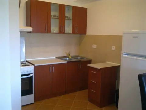 Simple kitchen with wooden cabinets and white appliances. - image 9