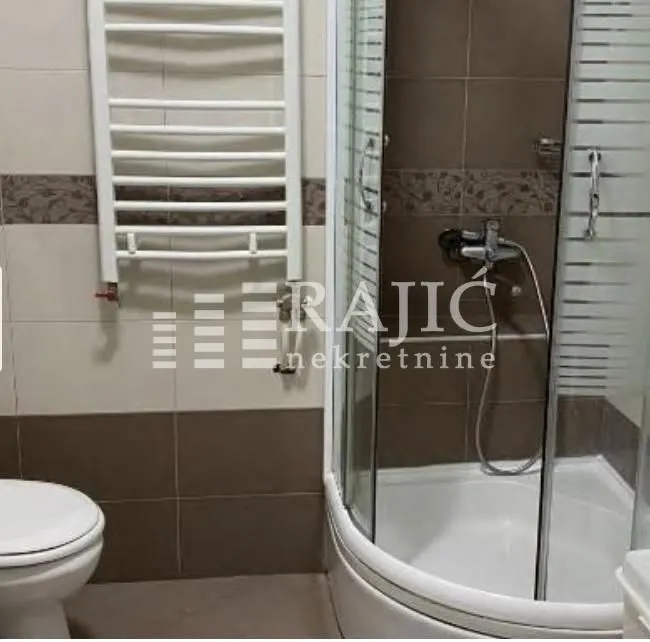 Smaller bathroom with a shower cabin, toilet, and towel radiator.