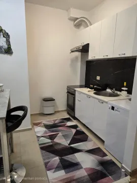 Small white kitchen with a stove and sink. - image 7