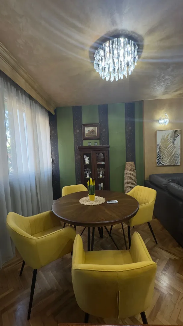 Dnevna soba sa trpezarijskim stolom i žutim foteljama.
