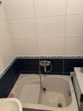 Manje kupatilo sa kadom obloženom pločicama i tuš baterijom. - image 3