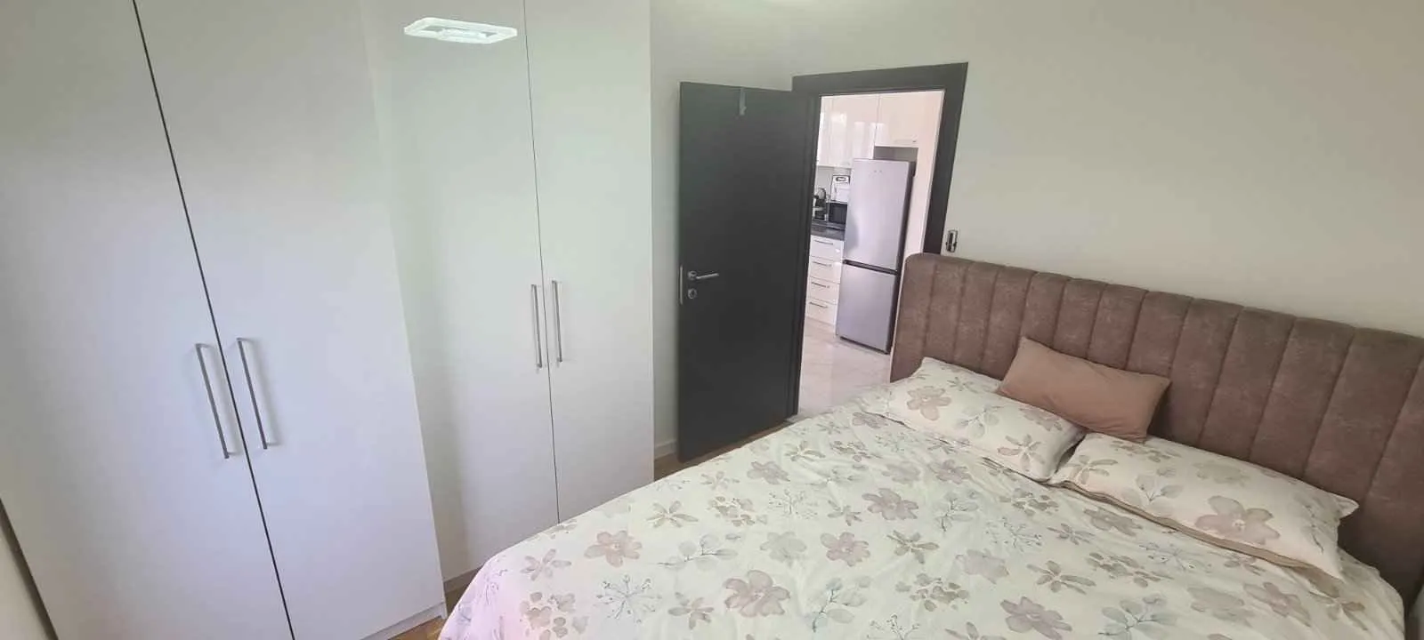Namještena spavaća soba sa bračnim krevetom i ugradnim plakarom.