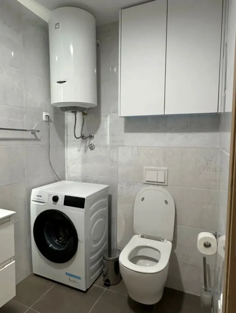 Manje kupatilo sa veš-mašinom, bojlerom i WC šoljom.