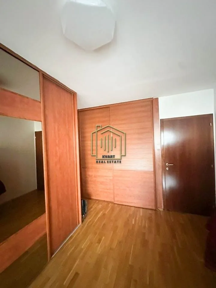 Spavaća soba sa ugradnim ormarima i drvenim podom.