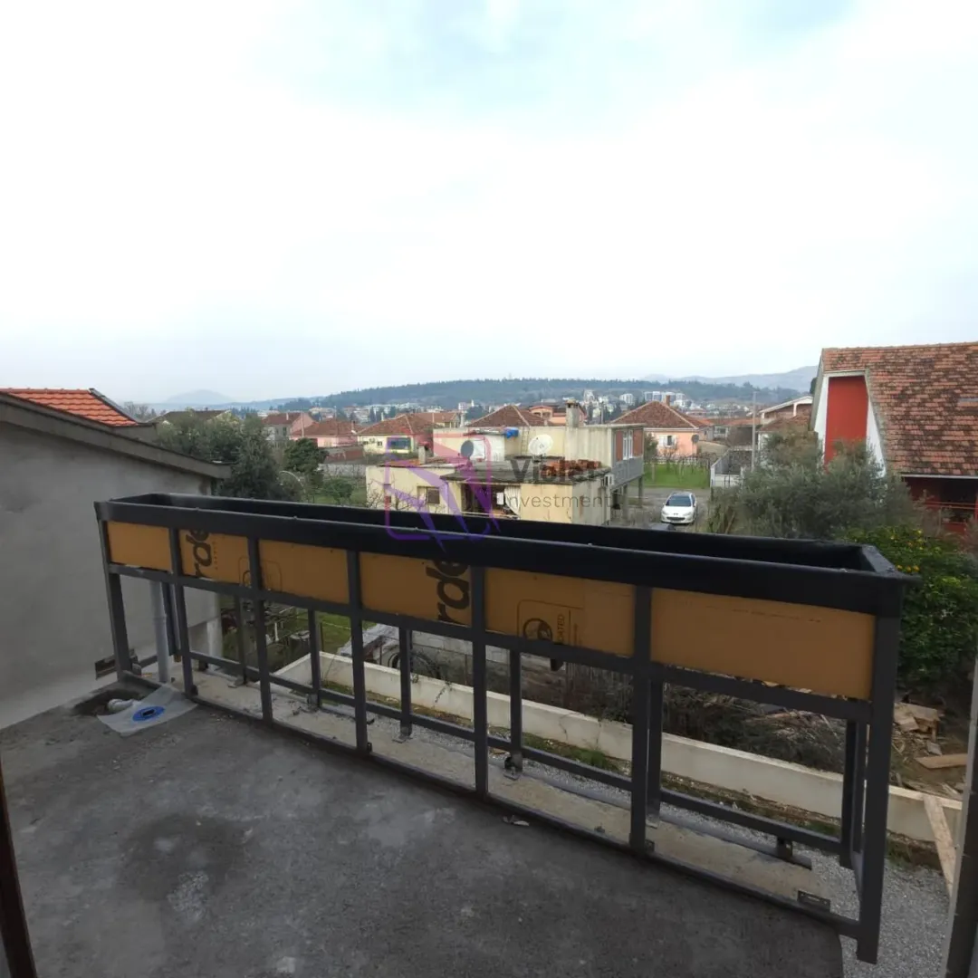 Unfinished balcony with a metal railing and a view of the surrounding neighborhood.