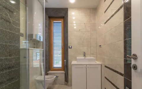 Moderno kupatilo sa svijetlim pločicama, umivaonikom i tuš kabinom. - image 12