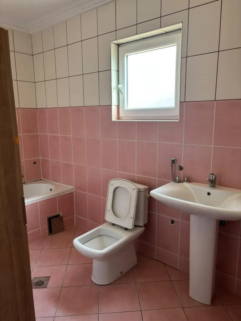 Bathroom tiled in pink and white with a bathtub, toilet, and sink.