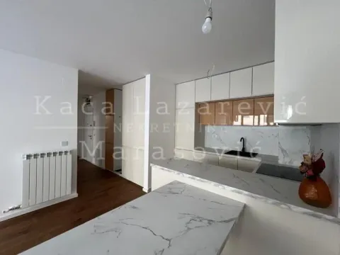 Moderna kuhinja sa belim elementima i šankom povezana sa hodnikom. - image 3