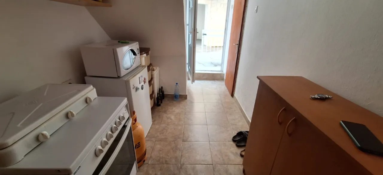 Pomoćna kuhinja sa šporetom, frižiderom i izlazom na spoljašnji prostor.