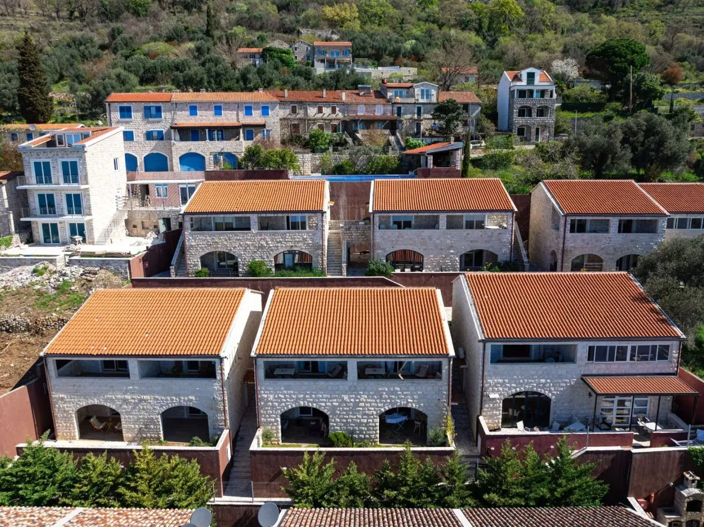 Pogled iz vazduha na kamene kuće sa crvenim krovovima u nizu.