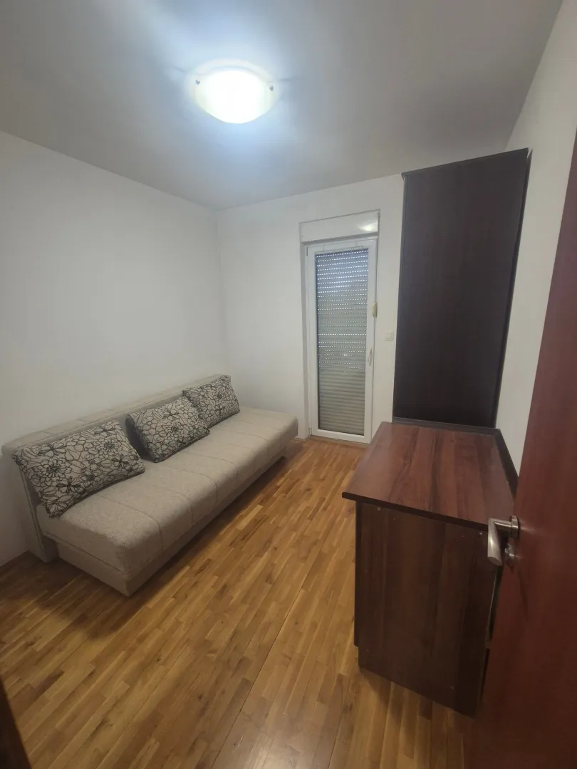 Manja spavaća soba sa kaučem i drvenim podom.