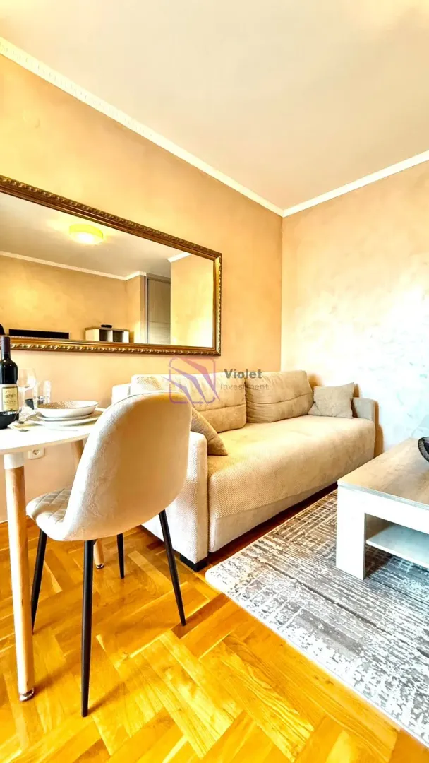 Living room with a sofa, dining table, and a large wall mirror.