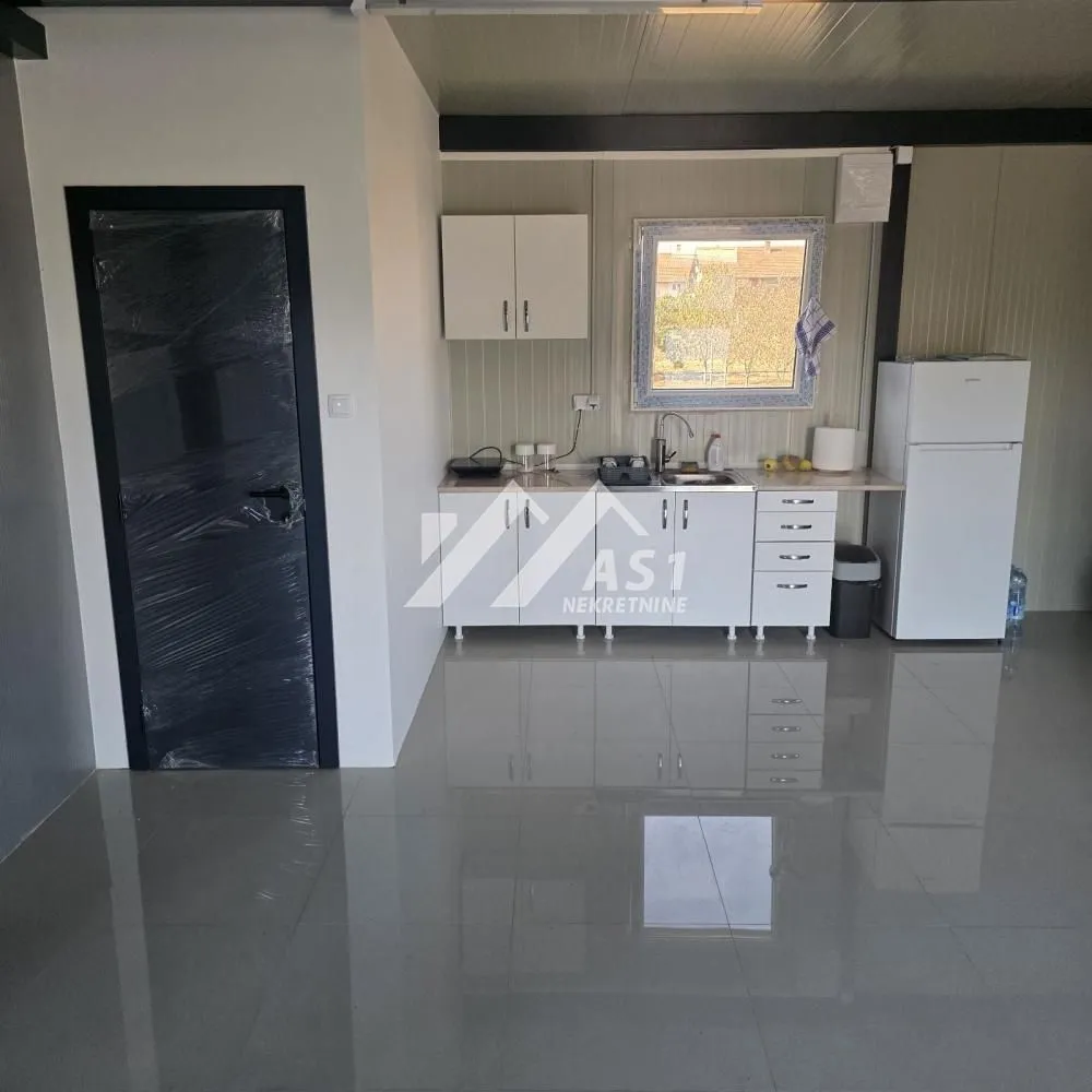 Small kitchen with white units and a refrigerator within the room.
