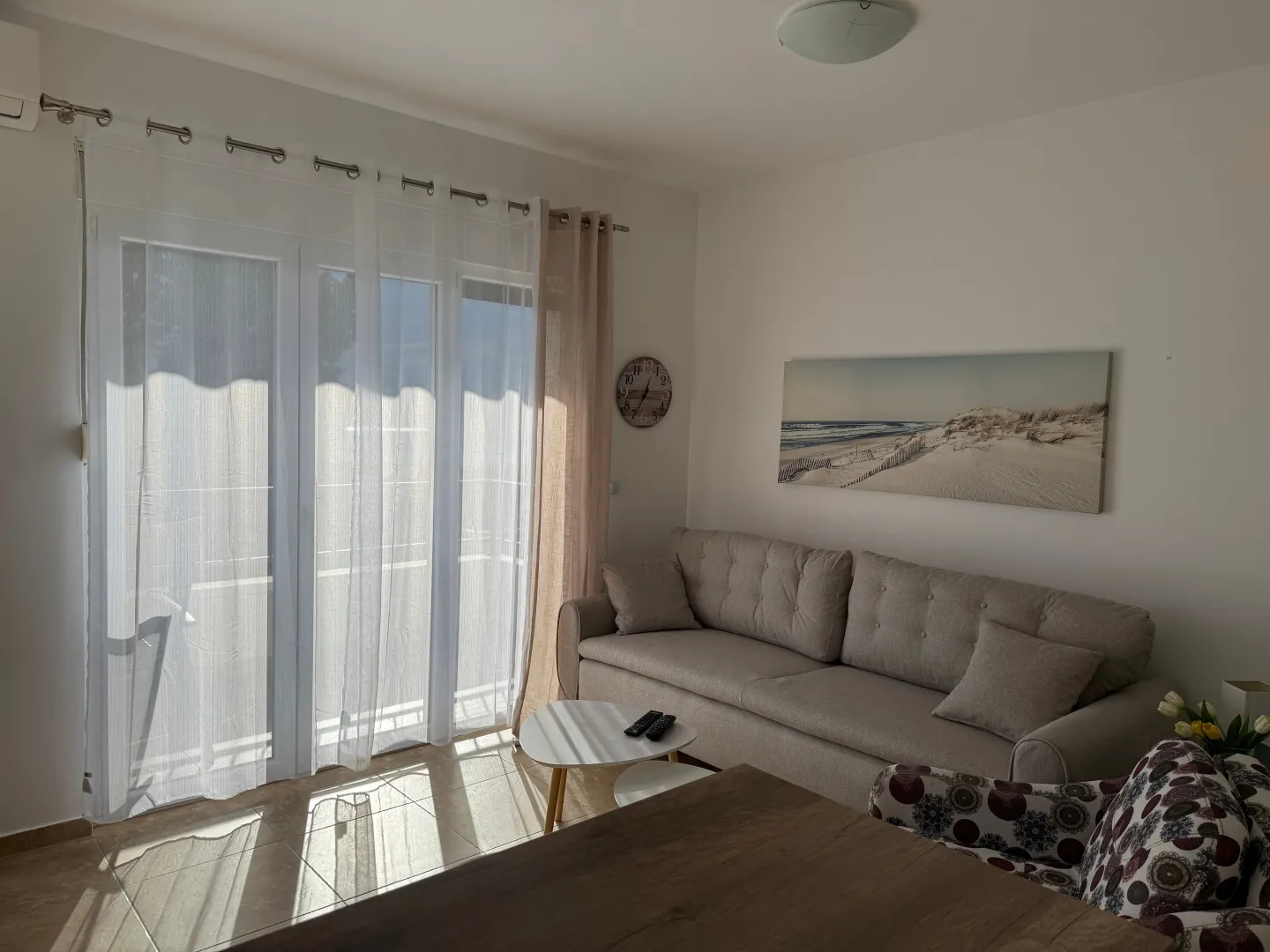 Dnevna soba sa garniturom, stočićem i izlazom na terasu.