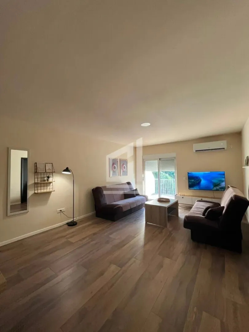 Spacious living room with seating furniture, a TV, and access to the terrace.