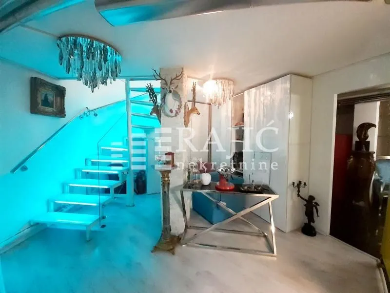 Living room with staircase and modern lighting.