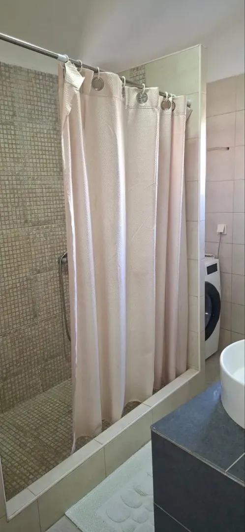 A view of the bathroom with a shower cabin and a washbasin.