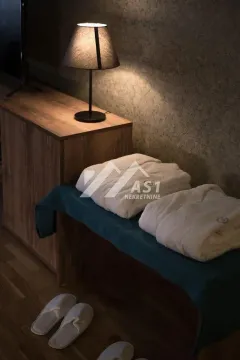 Detalj spavaće sobe sa uredno složenim peškirima, bade-mantilom i lampom na komodi. - image 7