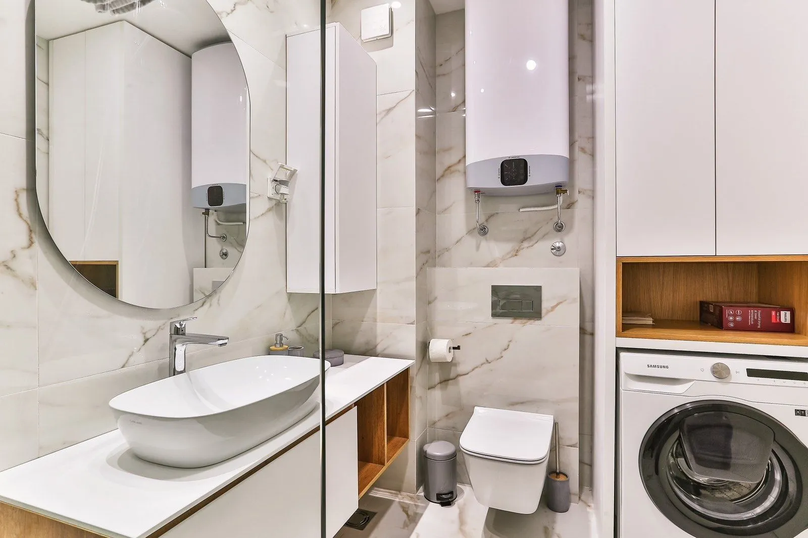 Modern bathroom with white marble tiles, a sink, and a washing machine.