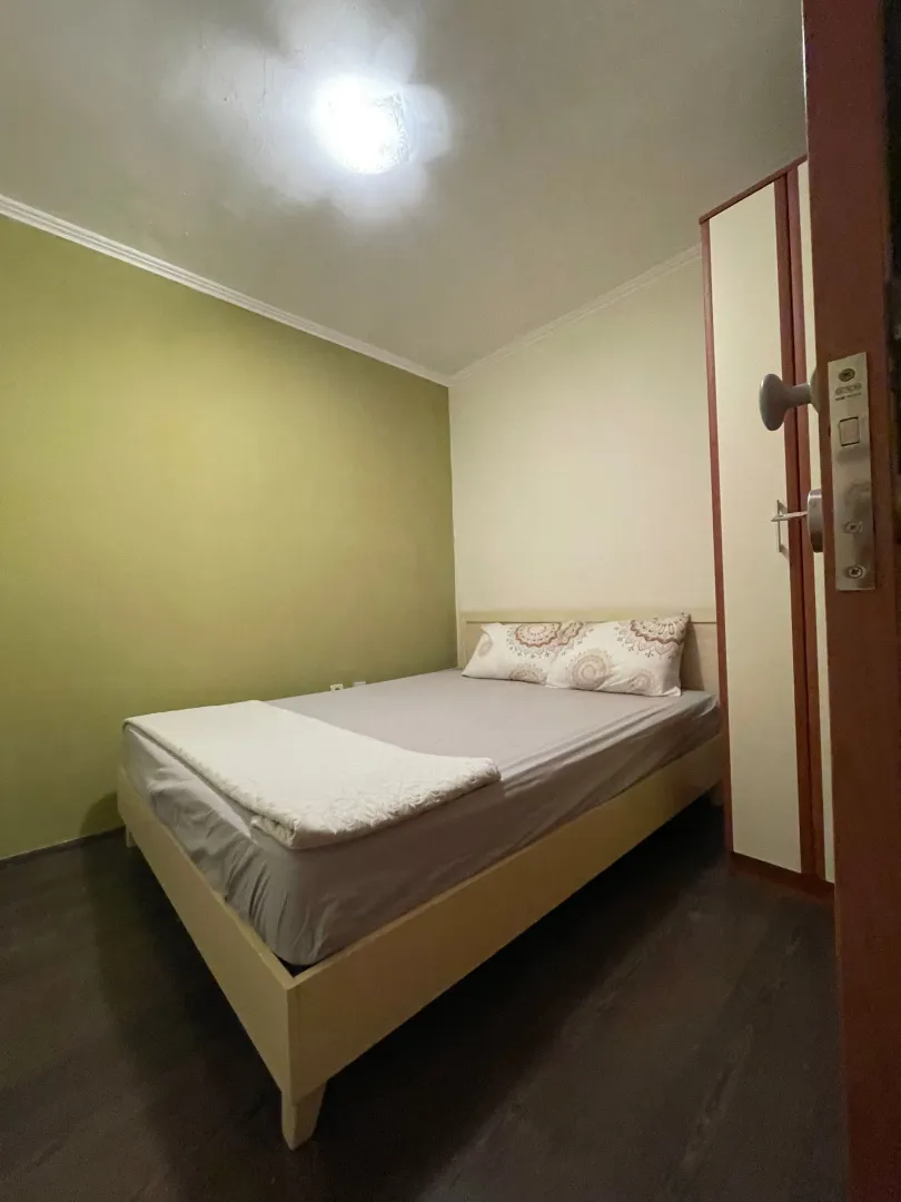 Manja spavaća soba sa bračnim krevetom i ormarom.