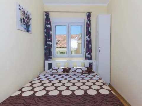 Manja spavaća soba sa bračnim krevetom, bijelim ormarom i prozorom. - image 5