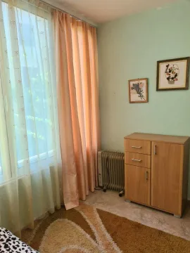 Manja soba sa drvenom komodom, radijatorom i prozorom sa zavjesama. - image 13