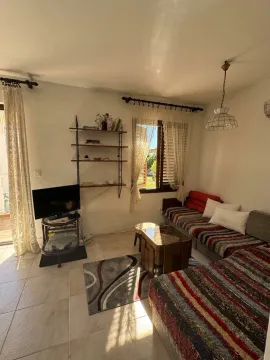 Living room with a sofa set, television, and a window with an outdoor view. - image 2